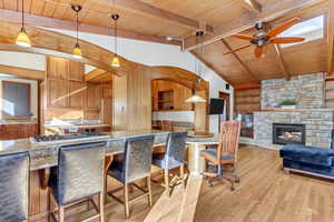 Kitchen with wood ceiling, stainless steel gas stovetop, light wood-type flooring, ceiling fan, and a fireplace