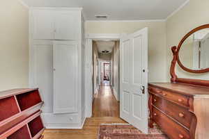 Hall featuring light wood-type flooring and ornamental molding