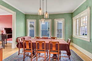 Dining area featuring wood finished floors, ornamental molding, and baseboards