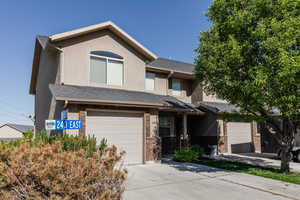 View of front of house with concrete driveway, brick siding, a garage, and stucco siding