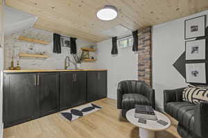 Bar area with a sink, wooden ceiling, and light wood-type flooring