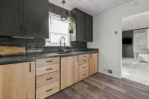 Remodeled kitchen with large sink, granite countertops, tasteful backsplash, dark wood-style floors, and modern style oak cabinets.