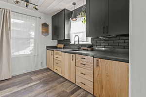 Remodeled kitchen with large sink, granite countertops, tasteful backsplash, dark wood-style floors, and modern style oak cabinets.
