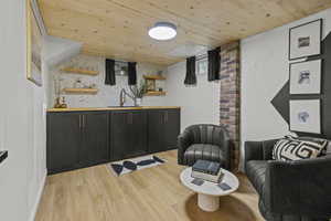 Bar featuring a sink, wood ceiling, and light wood finished floors