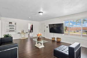 Living room with baseboards, built in features, wood finished floors, and a textured ceiling