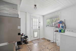 Foyer entrance featuring washer / clothes dryer, inlaid floor details, tile patterned floors, and baseboards