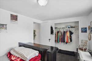Bedroom with wood finished floors, a closet, and baseboards