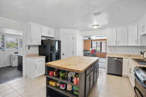 Kitchen featuring stainless steel appliances, white cabinets, butcher block counters, open shelves, and light tile patterned floors