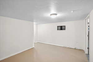 Finished basement with a textured ceiling and baseboards