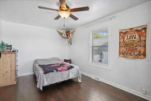 Bedroom featuring dark wood finished floors, baseboards, and ceiling fan