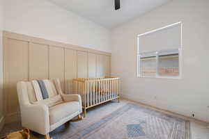 Bedroom with carpet floors, a decorative wall, ceiling fan, and a nursery area