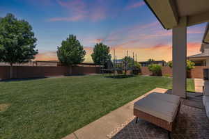 Yard at dusk featuring a trampoline and a patio