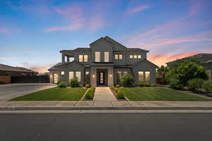 View of front facade featuring driveway, stucco siding, a standing seam roof, and metal roof