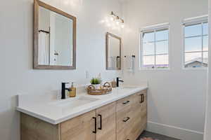 Bathroom with double vanity and baseboards