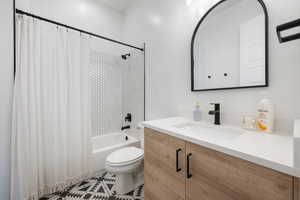 Full bath featuring vanity, shower / bath combo with shower curtain, and toilet