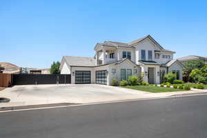 View of front of house with an attached garage, driveway, a gate, stucco siding, and a standing seam roof