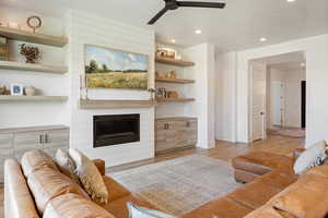 Living area with wood finished floors, a ceiling fan, baseboards, recessed lighting, and a large fireplace