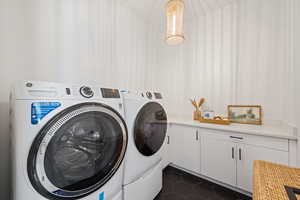 Laundry room featuring separate washer and dryer, dark tile patterned floors, and cabinet space