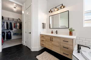 Bathroom featuring vanity, tile patterned flooring, a tub, a spacious closet, and baseboards