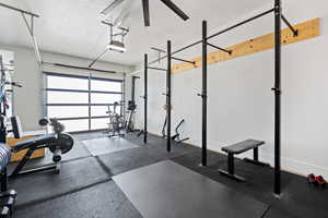 Workout room with a textured ceiling, a garage, and baseboards