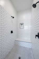 Full bathroom featuring a tile shower and tile patterned flooring