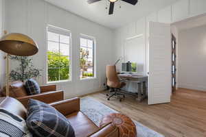 Office area featuring ceiling fan, a decorative wall, light wood-style flooring, and baseboards