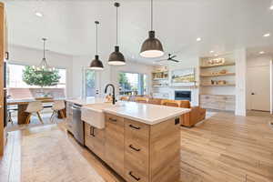 Kitchen with stainless steel dishwasher, a sink, an island with sink, recessed lighting, and light wood-style floors