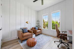 Office with a decorative wall, light wood-type flooring, and ceiling fan