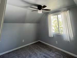 Bonus room with a ceiling fan, vaulted ceiling, dark carpet, and baseboards