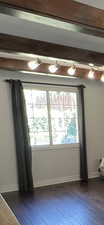 Unfurnished room with healthy amount of natural light, dark wood-type flooring, and baseboards