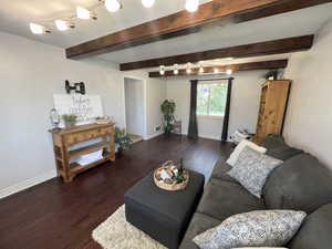 Living room with wood finished floors, baseboards, and beamed ceiling