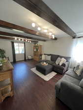 Living area with beam ceiling, dark wood-style floors, and baseboards