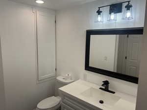 Bathroom with vanity, toilet, and recessed lighting