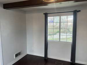 Spare room with baseboards, dark wood-type flooring, and beam ceiling