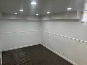 Empty room featuring recessed lighting, dark colored carpet, and baseboards