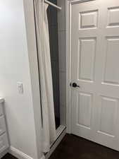 Bathroom with a shower with shower curtain and wood finished floors