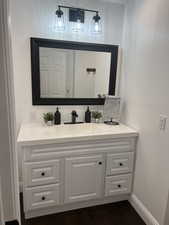 Bathroom with vanity, wood finished floors, and baseboards