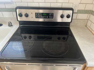 Kitchen view of stainless steel electric range and decorative backsplash