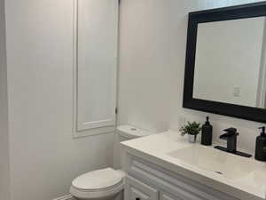 Bathroom featuring wood finished floors, vanity, toilet, baseboards, and recessed lighting