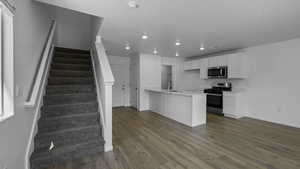 Kitchen with appliances with stainless steel finishes, recessed lighting, light countertops, white cabinetry, and dark wood-type flooring