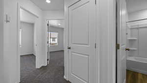 Hall with dark carpet, recessed lighting, and baseboards