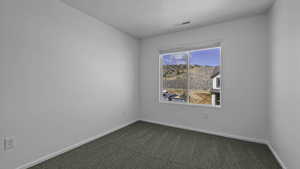 Empty room with dark carpet and baseboards