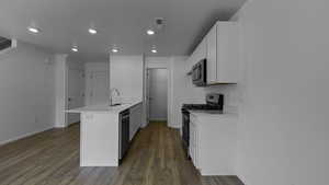 Kitchen with appliances with stainless steel finishes, a peninsula, baseboards, a sink, and recessed lighting