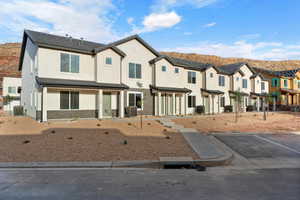 Multi unit property featuring stucco siding, a residential view, uncovered parking, a mountain view, and brick siding