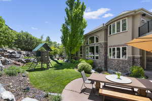 View of green lawn featuring a playground, a patio, and outdoor dining area