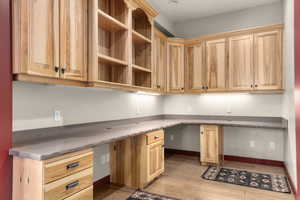 Unfurnished office featuring built in desk, light wood-style flooring, and baseboards