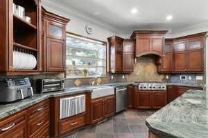 Kitchen featuring stainless steel appliances, a warming drawer, crown molding, decorative backsplash, and a sink
