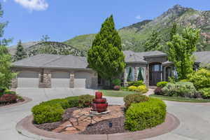 View of front facade featuring stone siding, a garage, a mountain view, and concrete driveway