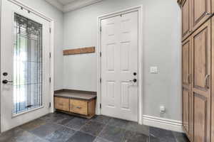 Entrance foyer featuring stone tile floors and baseboards
