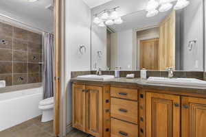 Full bathroom with double vanity, toilet, tile patterned flooring, and shower / bath combo